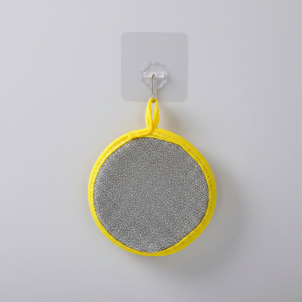 Round cleaning pad with yellow border attached to a hook on a tiled wall.