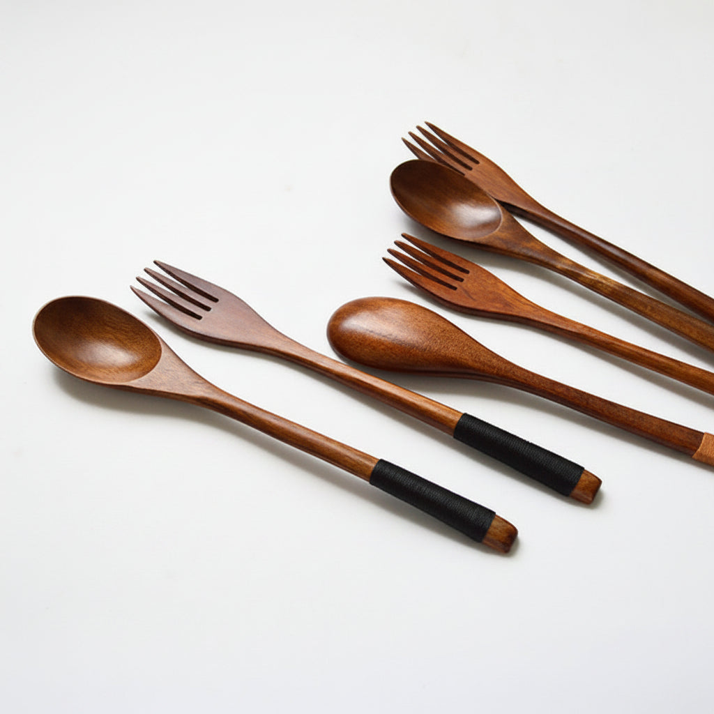 Set of wooden spoons and forks with black handles on a white background