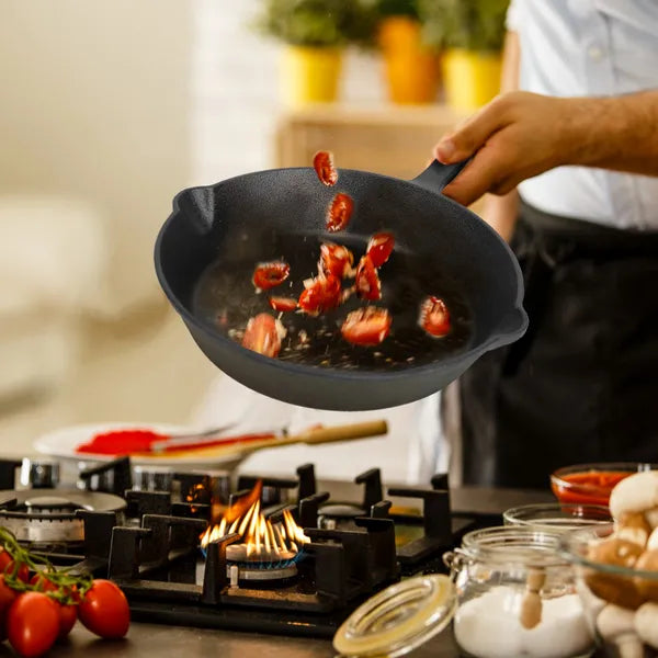 Person cooking bacon in a frying pan on a stove with a blurred kitchen background