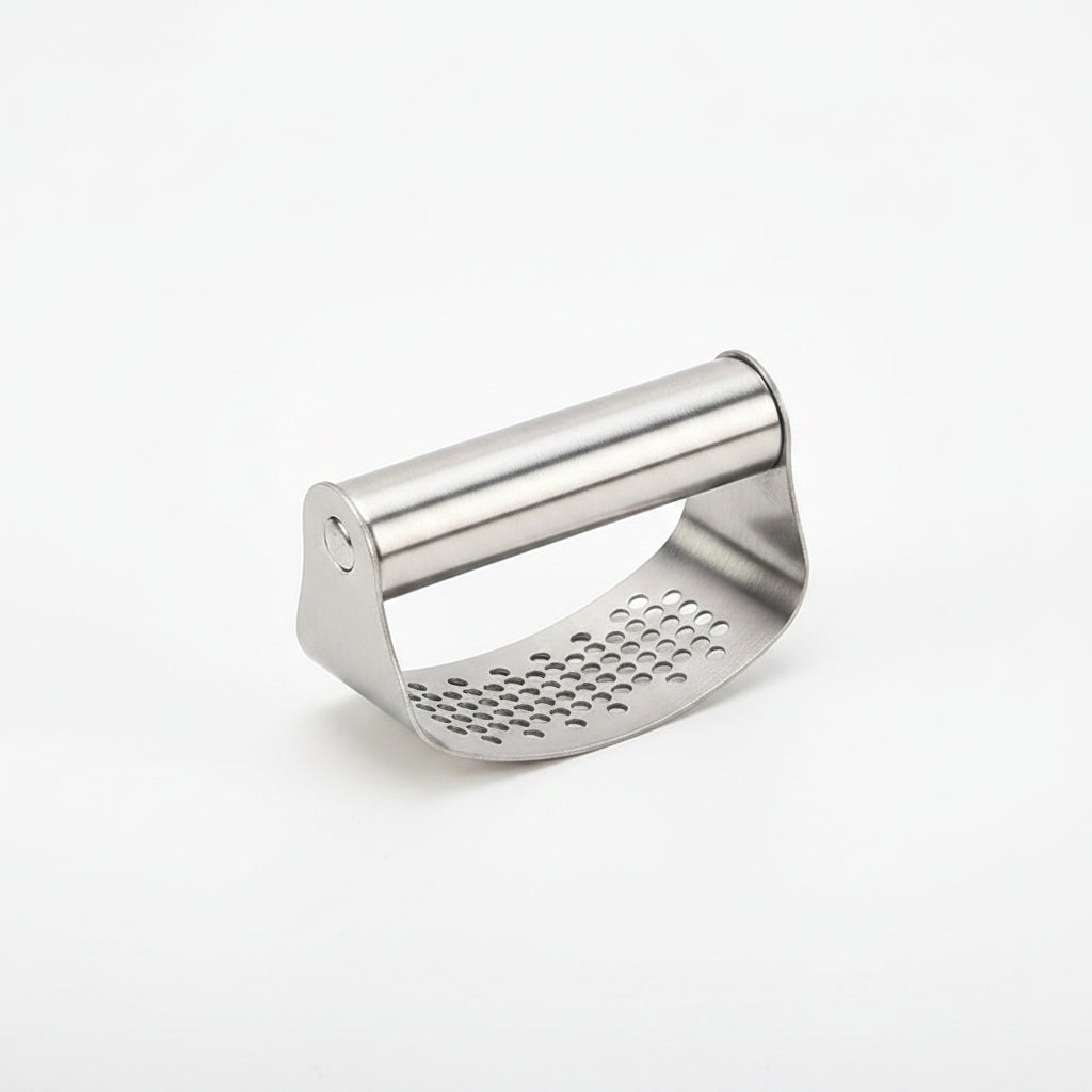 Metal grater on a white surface with vegetables and a green cutting board in the background.