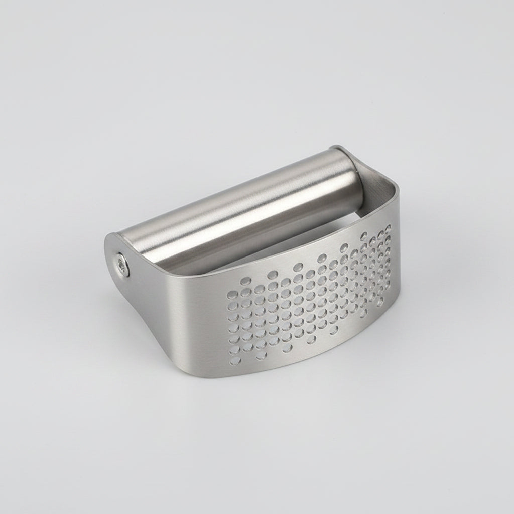 Metal vegetable peeler on a white surface with vegetables in the background