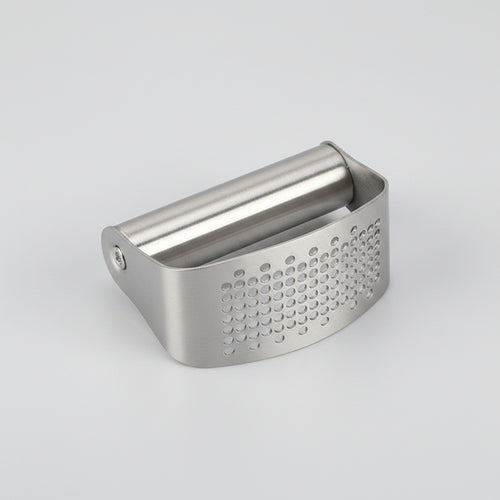 Metal vegetable peeler on a white surface with vegetables in the background