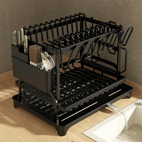 Black dish rack with cutlery and dishes on a wooden countertop.